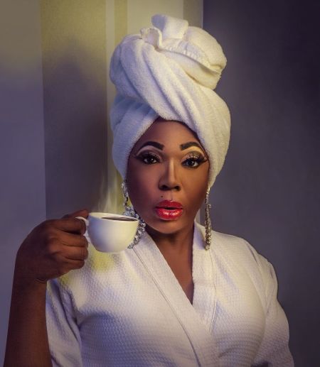 Dragnificent cast Bebe Zahara Benet in a gown drinking tea.